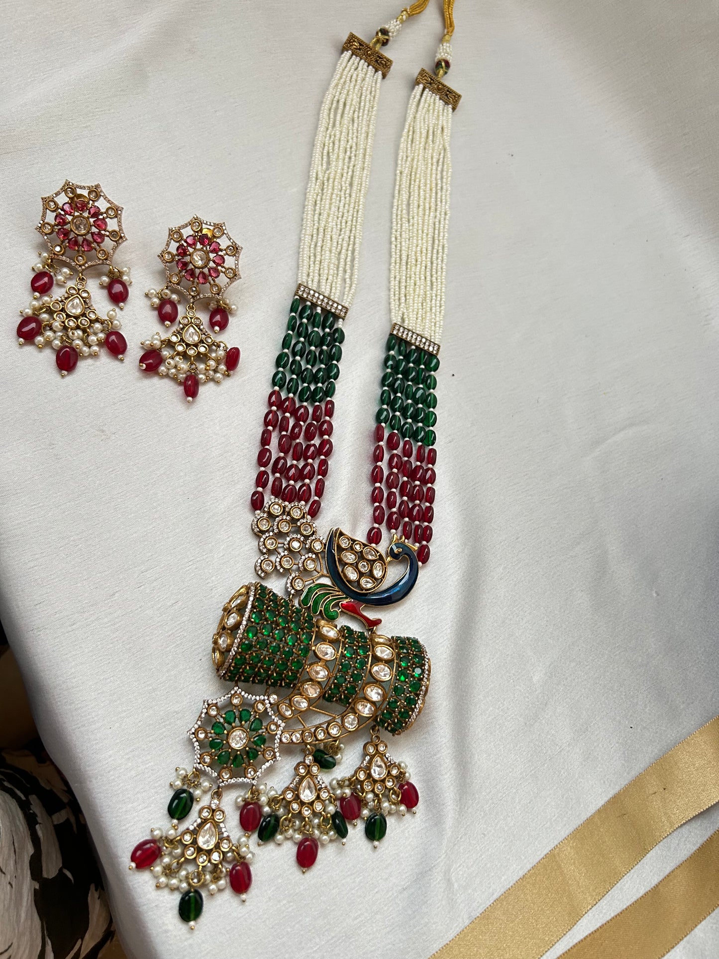 Kundan Rani Haar set with ivory pearl strands, red and green beads, and intricate gold detailing, paired with statement earrings.