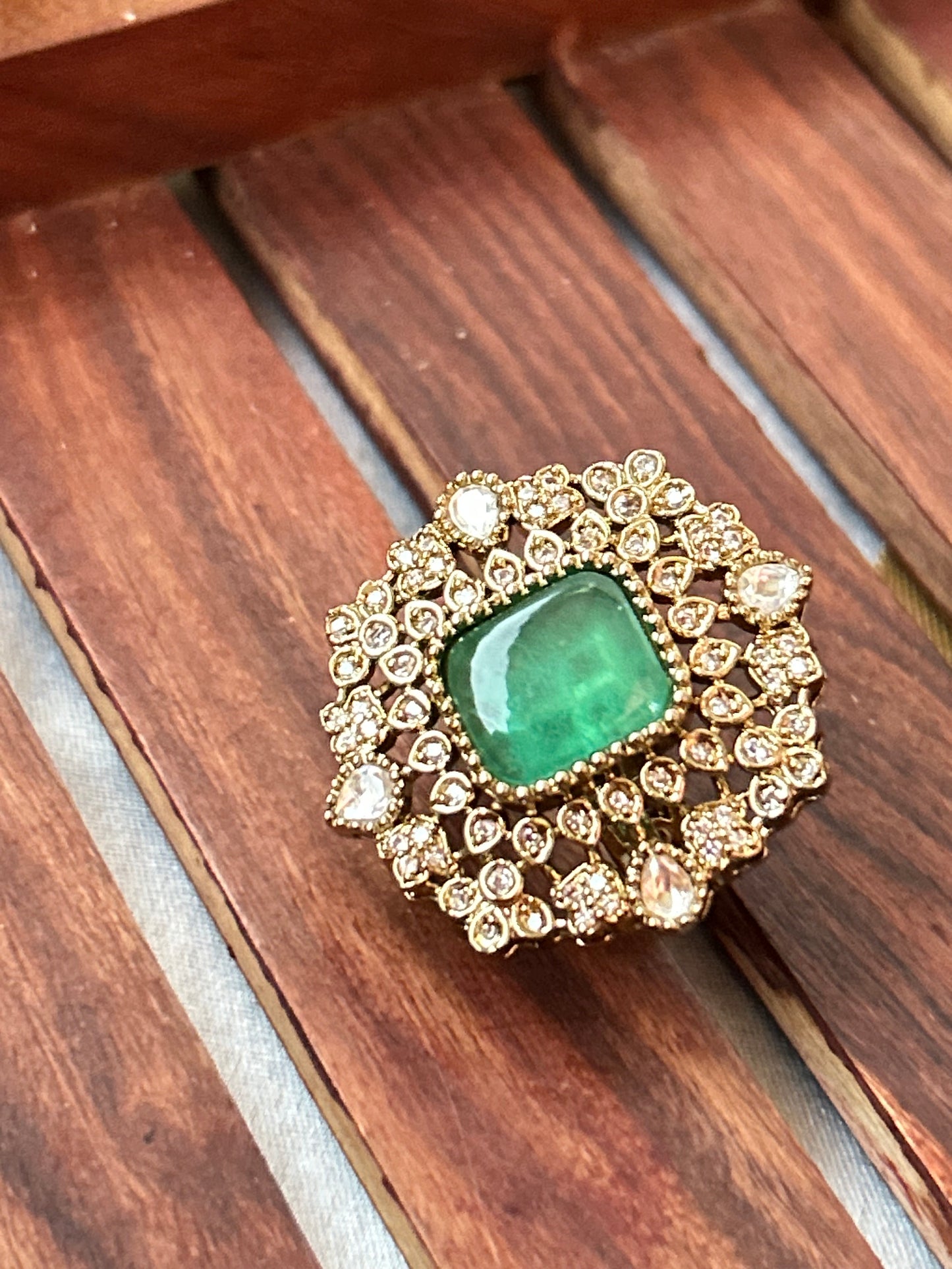 Square-cut emerald green ring with intricate gold and American diamond detailing