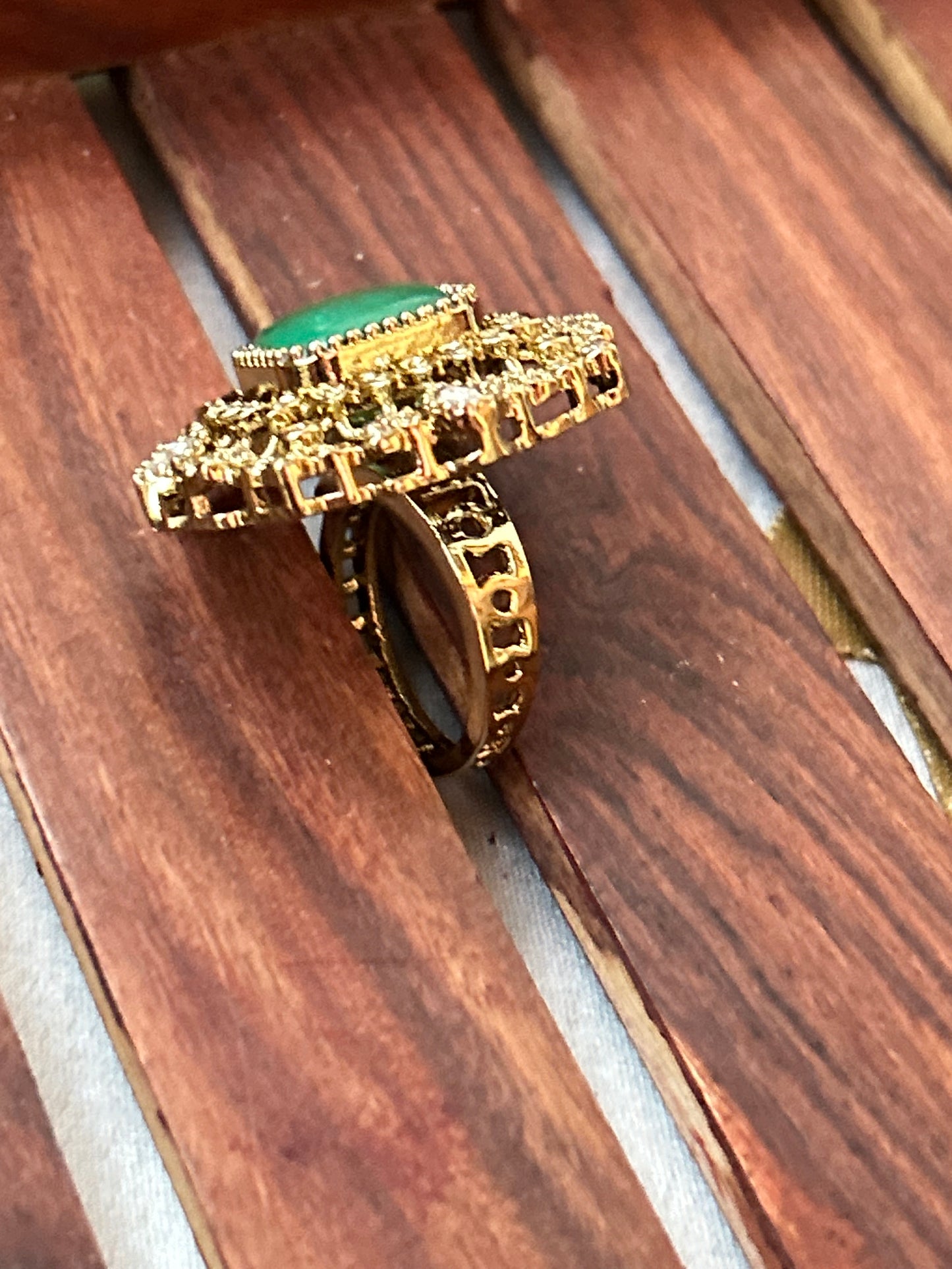 Square-cut emerald green ring with intricate gold and American diamond detailing
