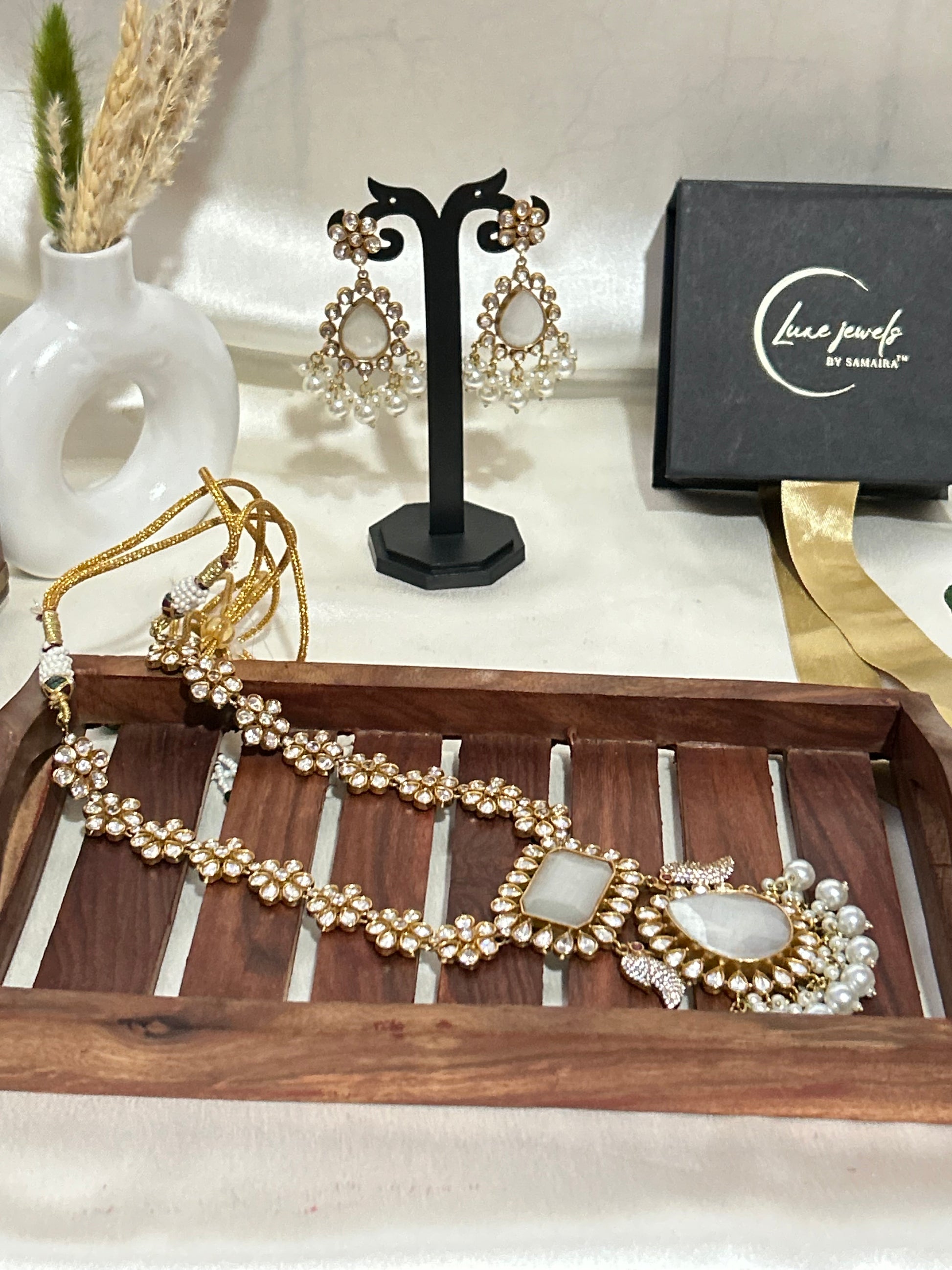 A luxurious Maharani-style Kundan necklace set with intricate floral motifs, ivory centerpiece stones, and pearl embellishments, paired with matching pearl-studded earrings for a royal look.