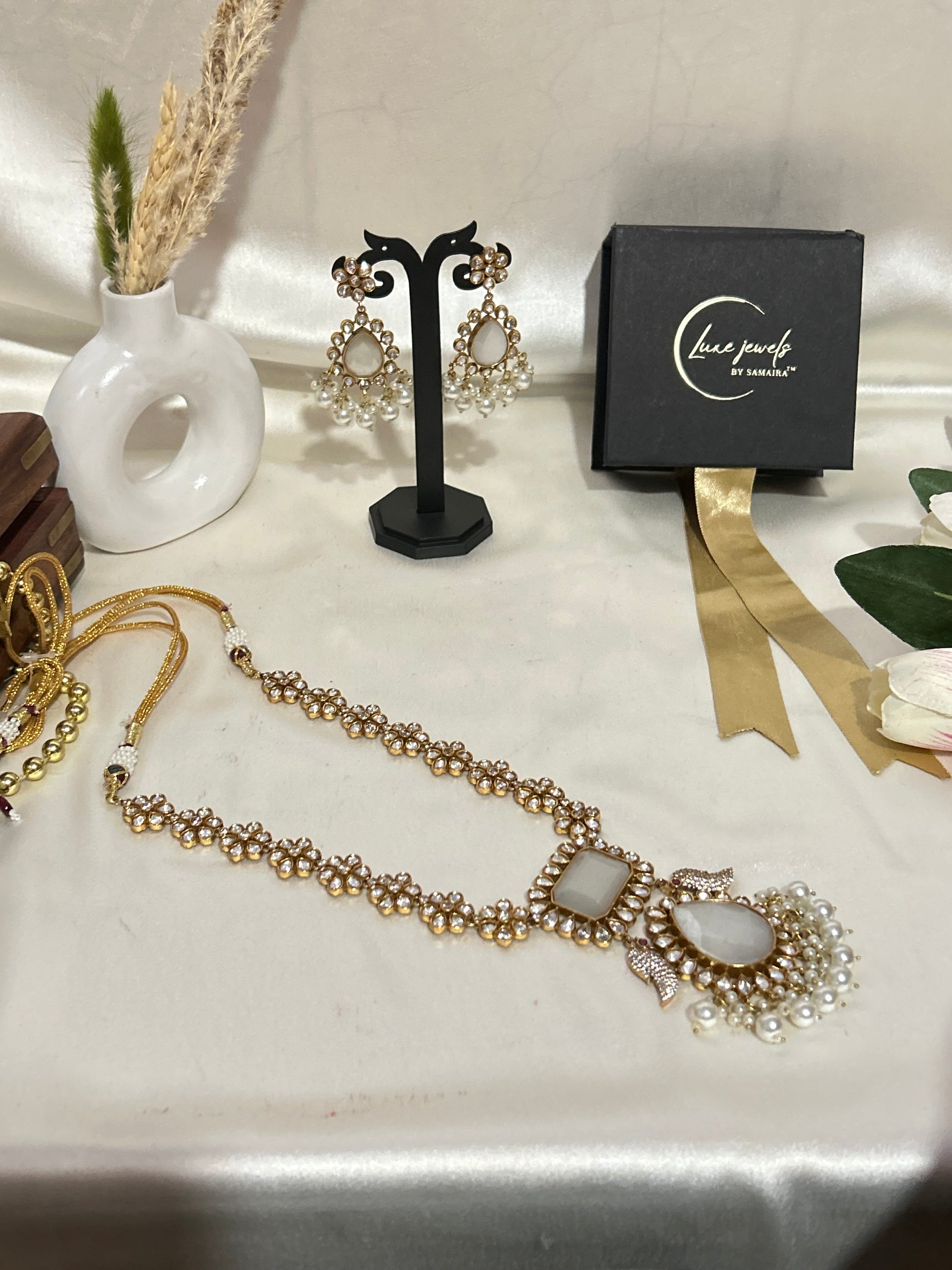 A luxurious Maharani-style Kundan necklace set with intricate floral motifs, ivory centerpiece stones, and pearl embellishments, paired with matching pearl-studded earrings for a royal look.