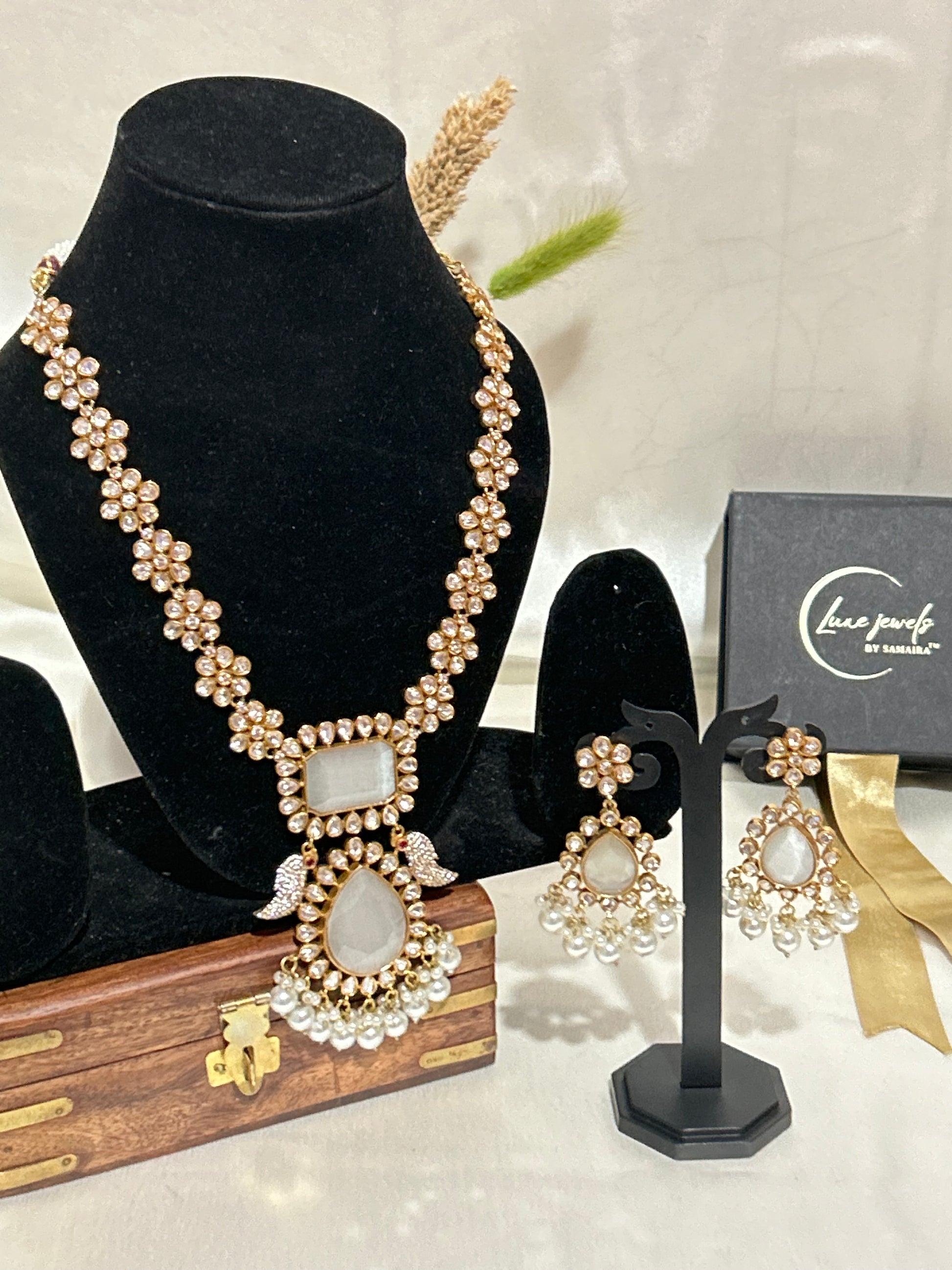 A luxurious Maharani-style Kundan necklace set with intricate floral motifs, ivory centerpiece stones, and pearl embellishments, paired with matching pearl-studded earrings for a royal look.