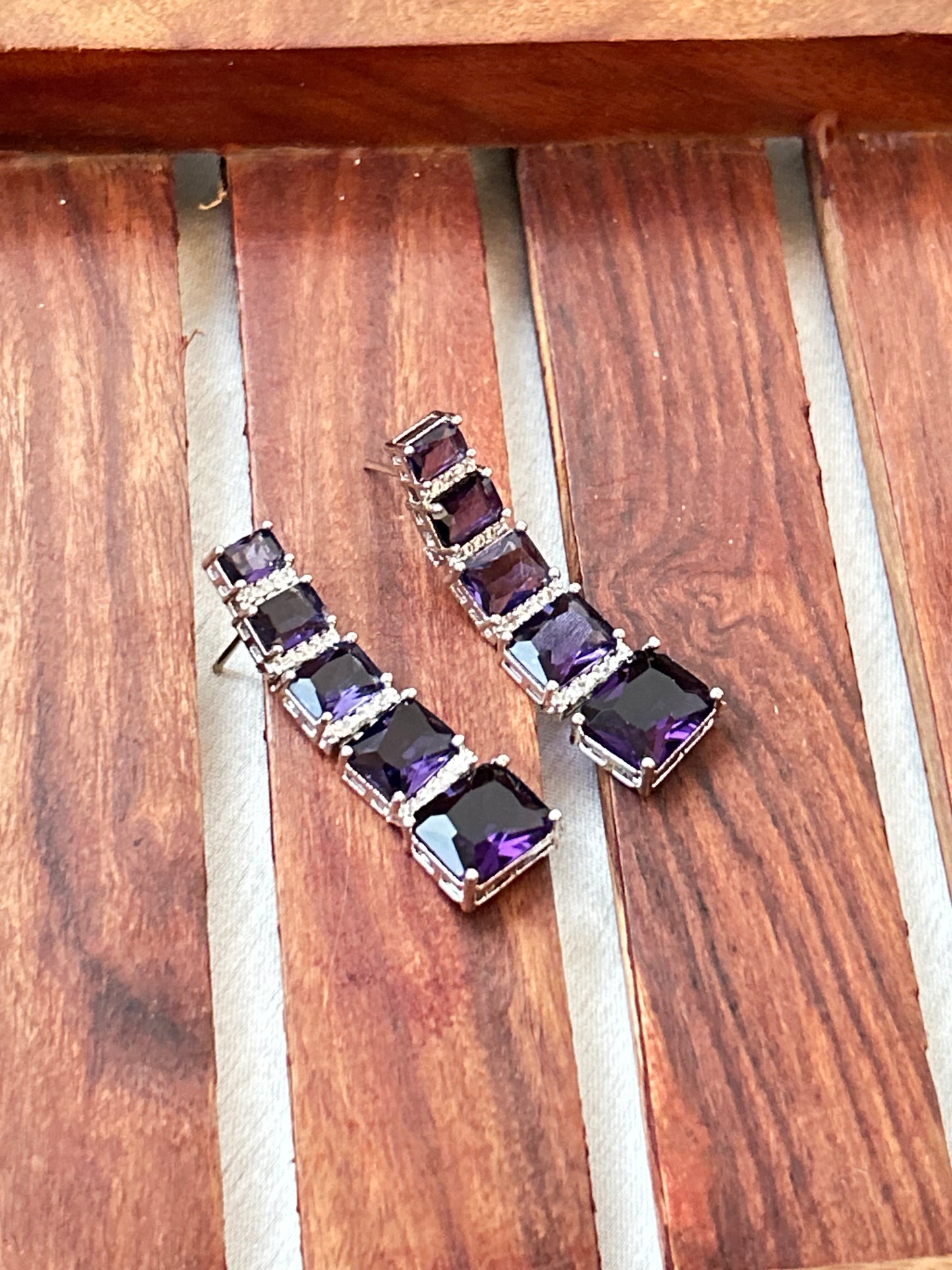 Long violet-purple earrings with American diamonds and white gold plating.