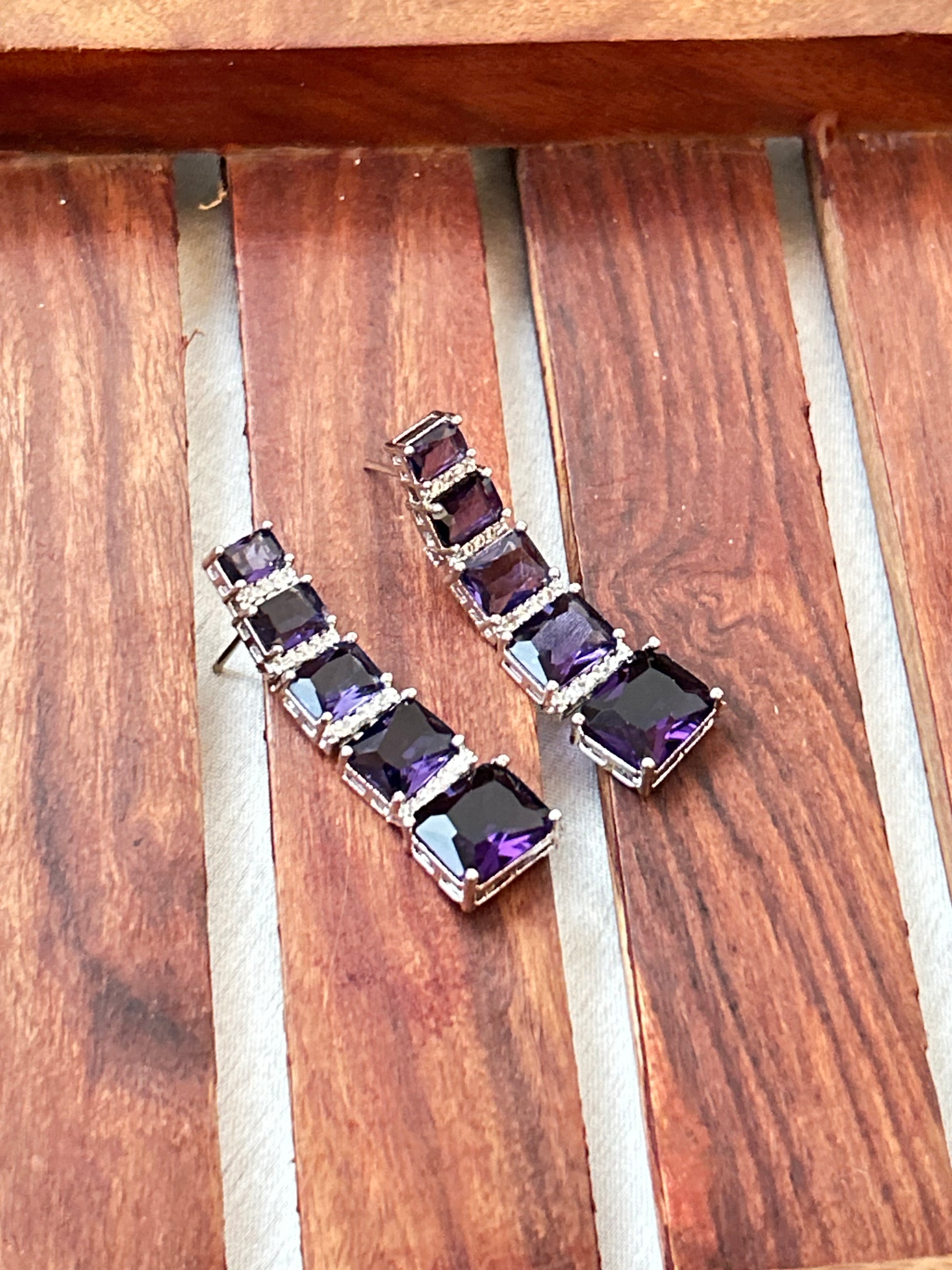 Long violet-purple earrings with American diamonds and white gold plating.