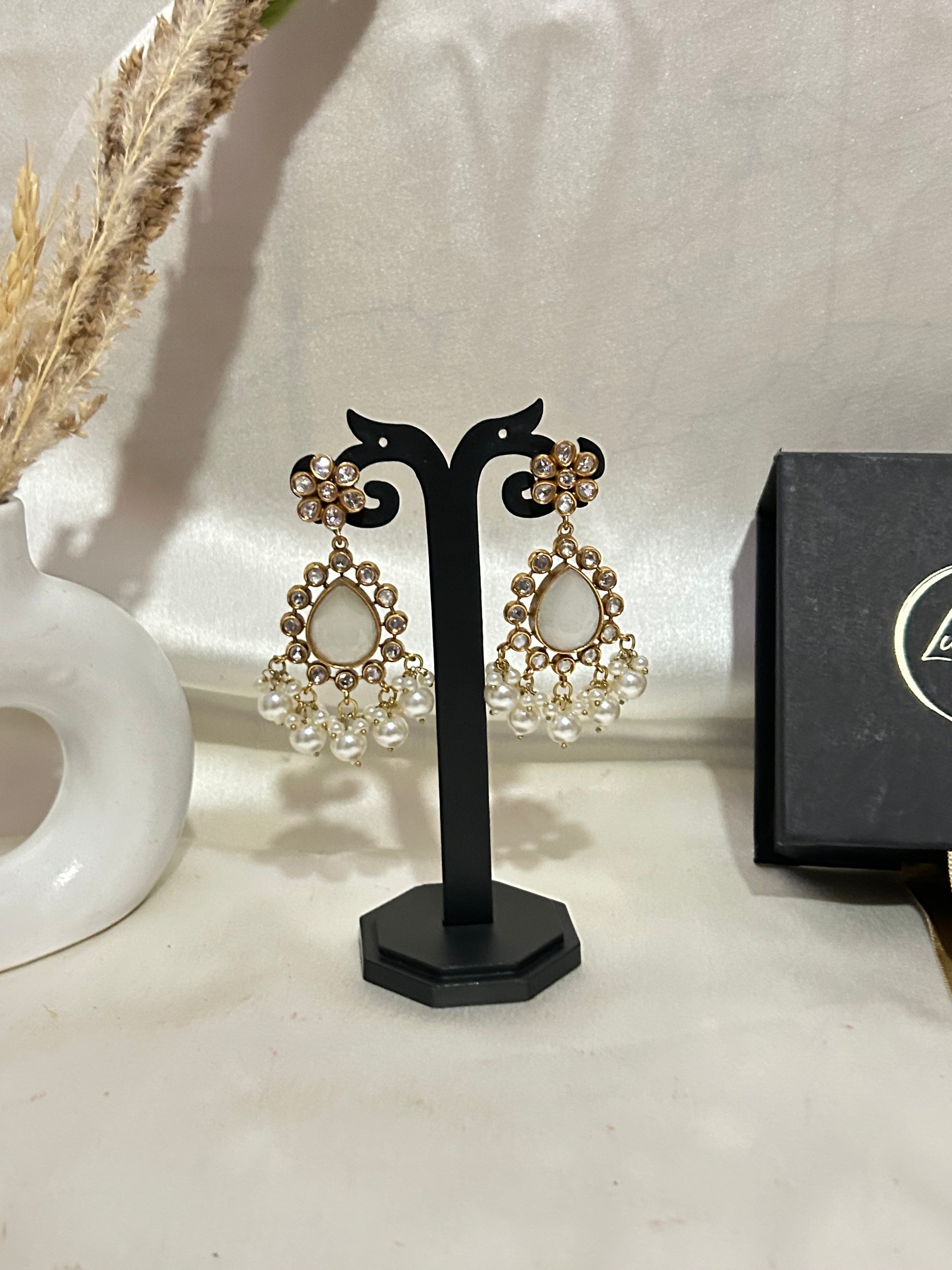 A luxurious Maharani-style Kundan necklace set with intricate floral motifs, ivory centerpiece stones, and pearl embellishments, paired with matching pearl-studded earrings for a royal look.
