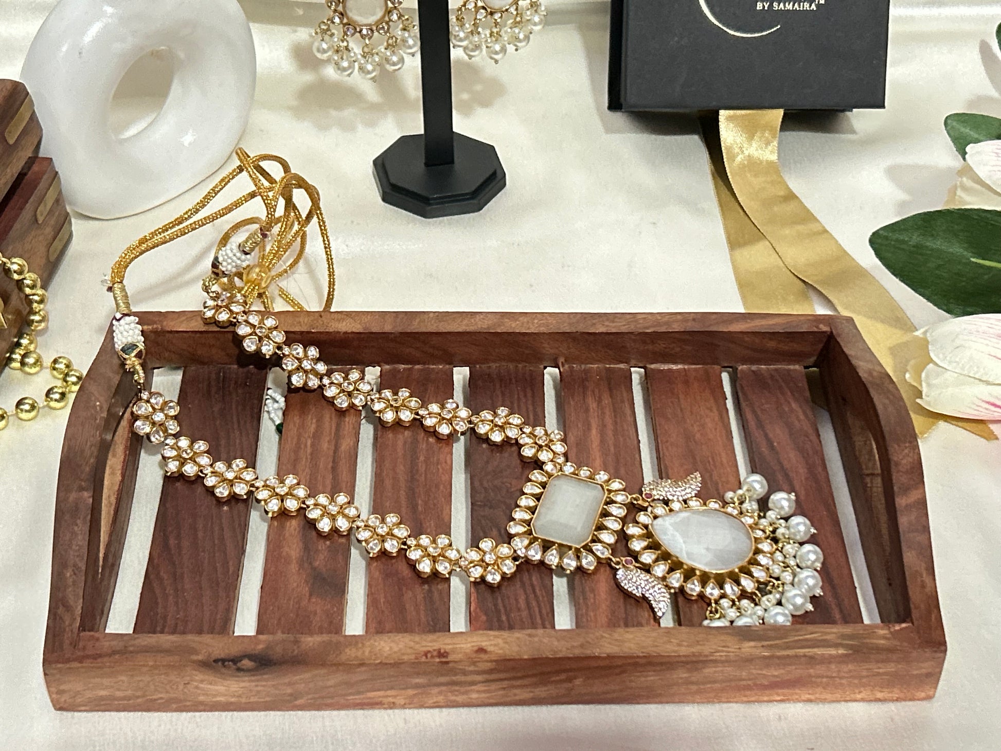 A luxurious Maharani-style Kundan necklace set with intricate floral motifs, ivory centerpiece stones, and pearl embellishments, paired with matching pearl-studded earrings for a royal look.