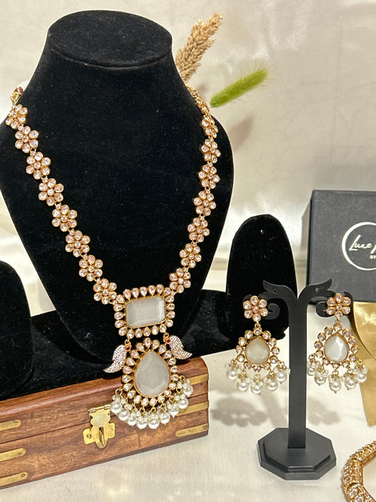 A luxurious Maharani-style Kundan necklace set with intricate floral motifs, ivory centerpiece stones, and pearl embellishments, paired with matching pearl-studded earrings for a royal look.