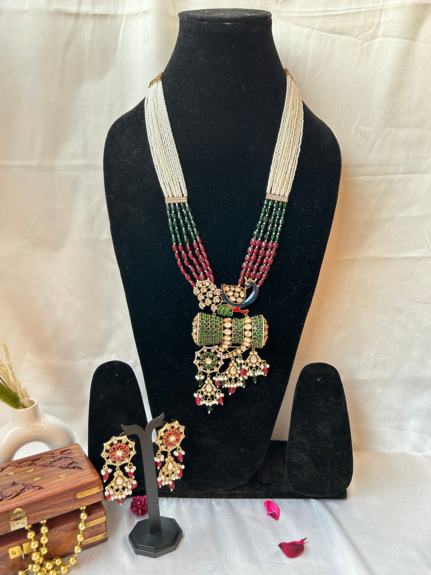  Kundan Rani Haar set with ivory pearl strands, red and green beads, and intricate gold detailing, paired with statement earrings.