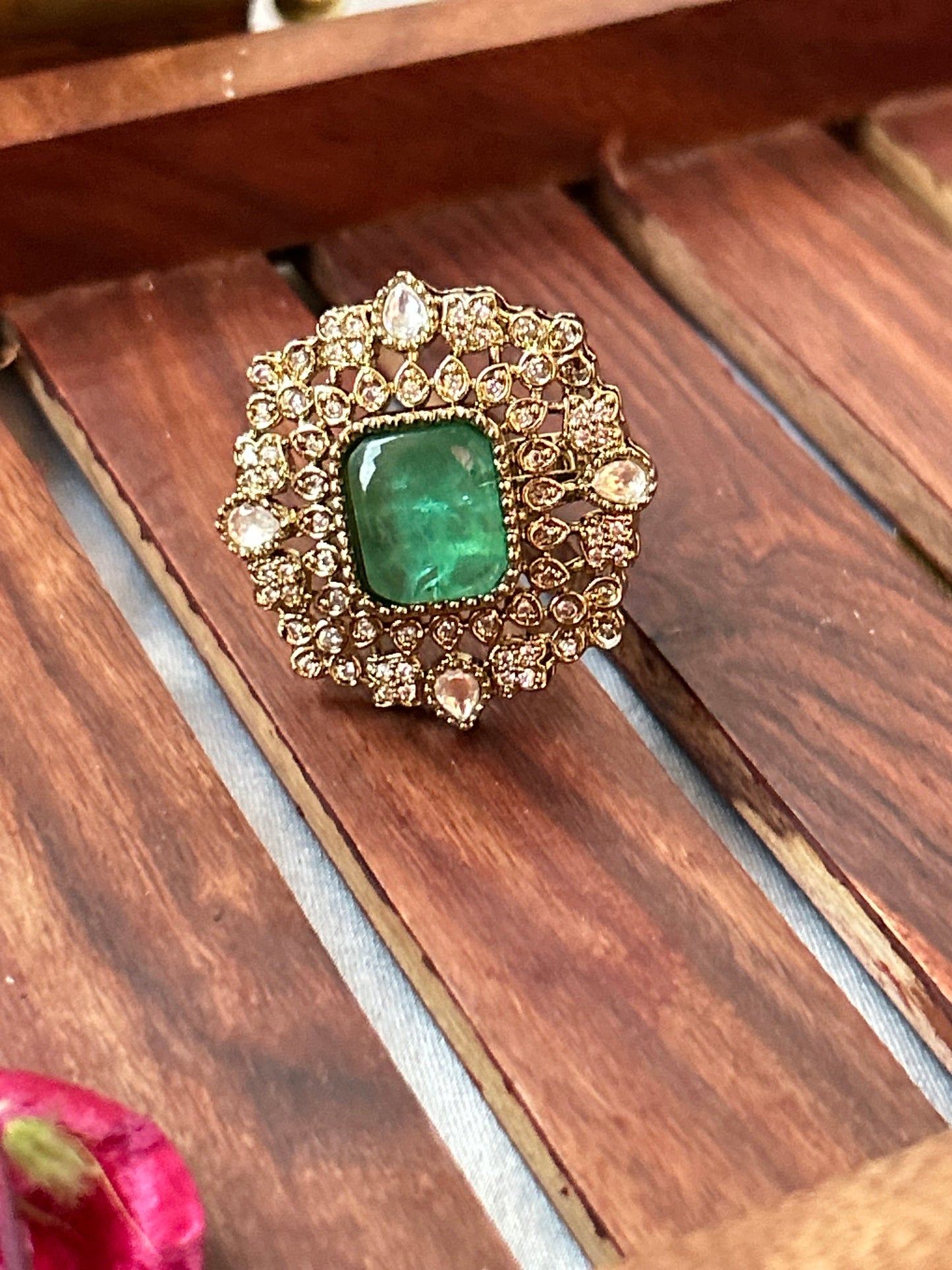 Square-cut emerald green ring with intricate gold and American diamond detailing  
