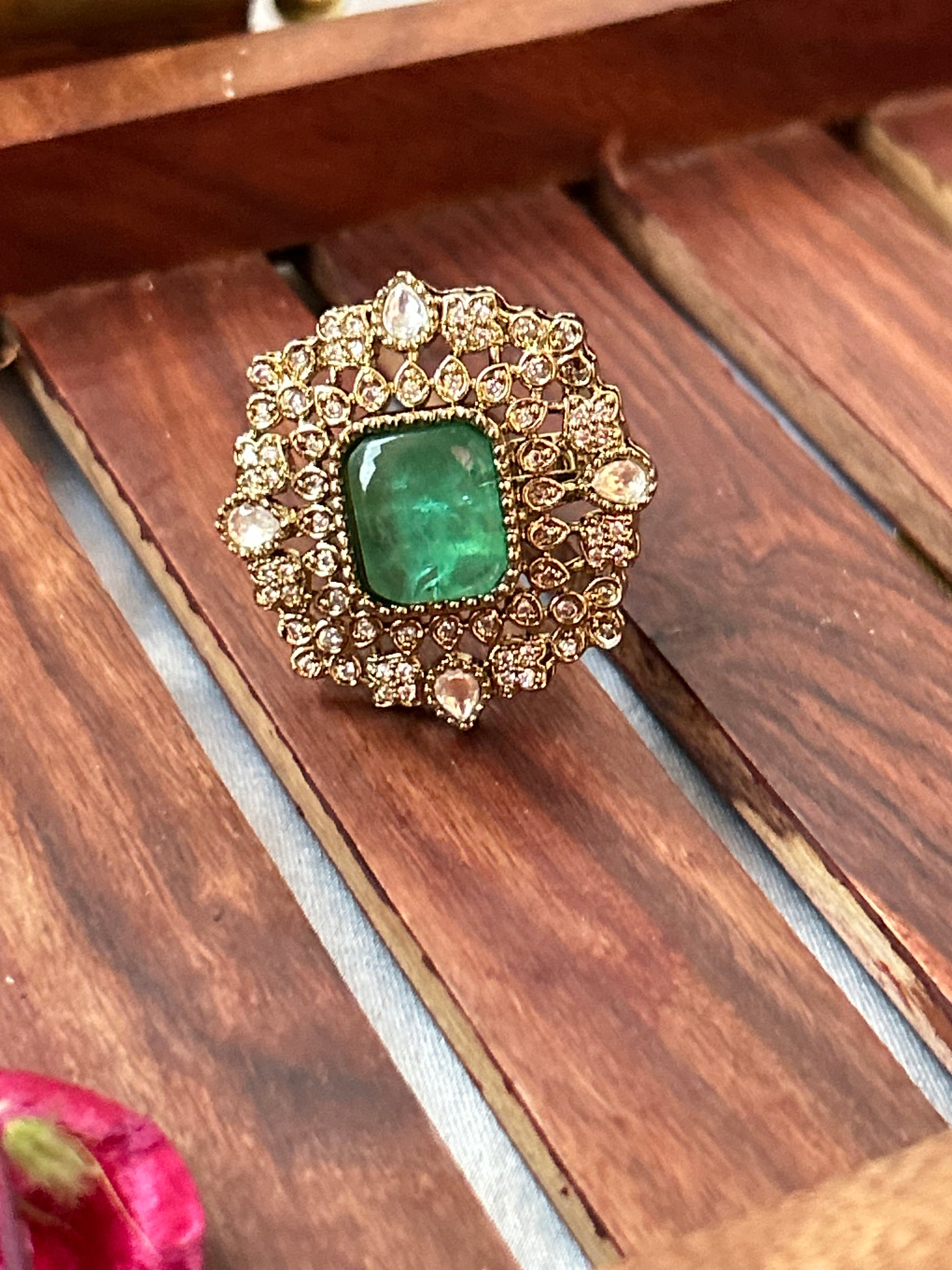 Square-cut emerald green ring with intricate gold and American diamond detailing  